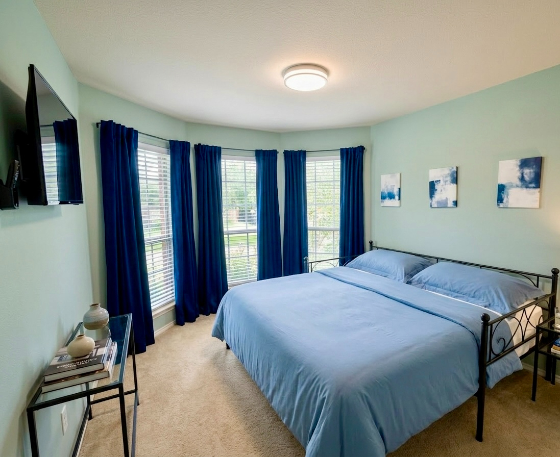 Bedroom with queen bed, bay windows and navy curtains