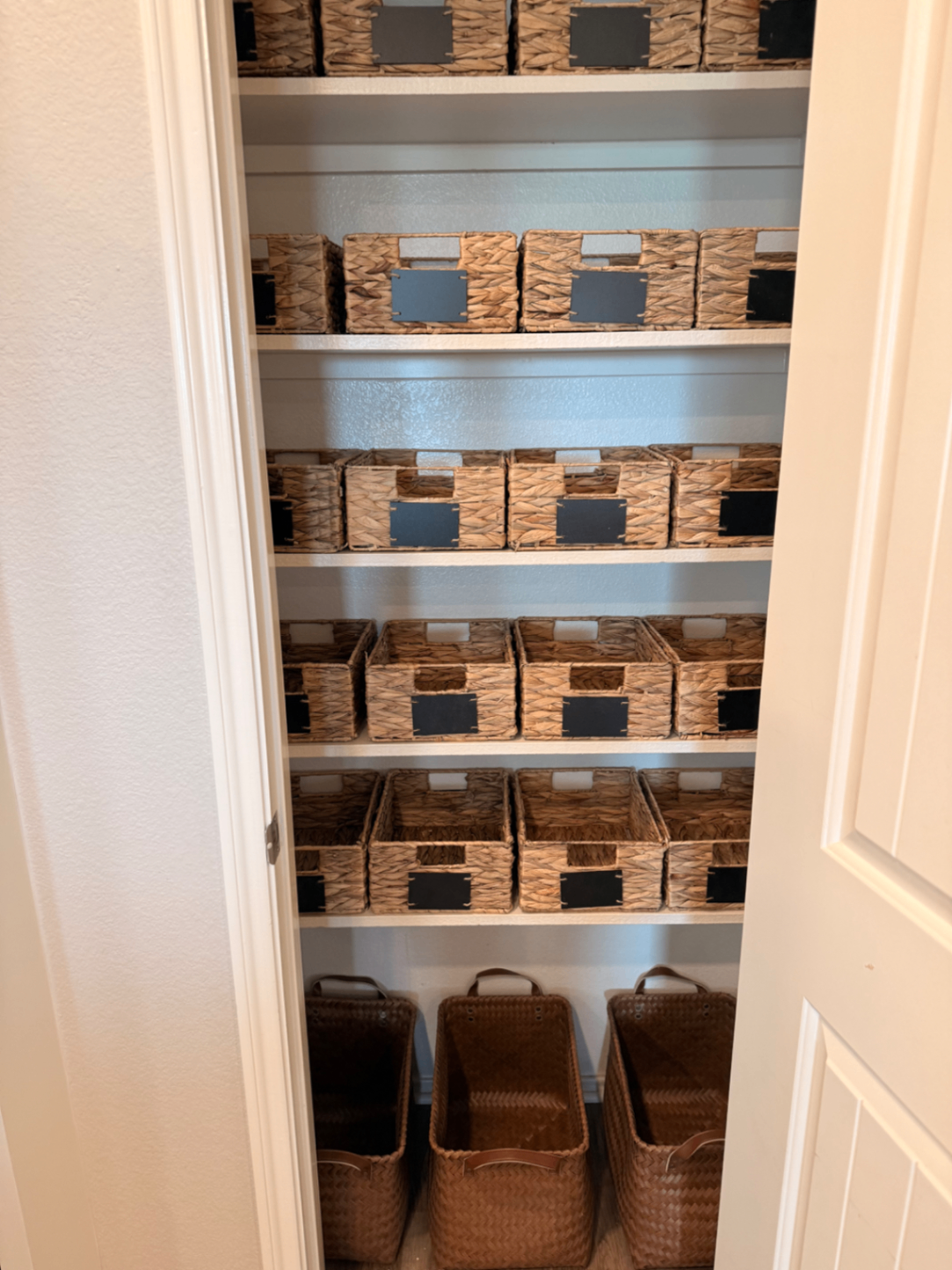 Walk-in pantry shelves lined with labeled woven baskets