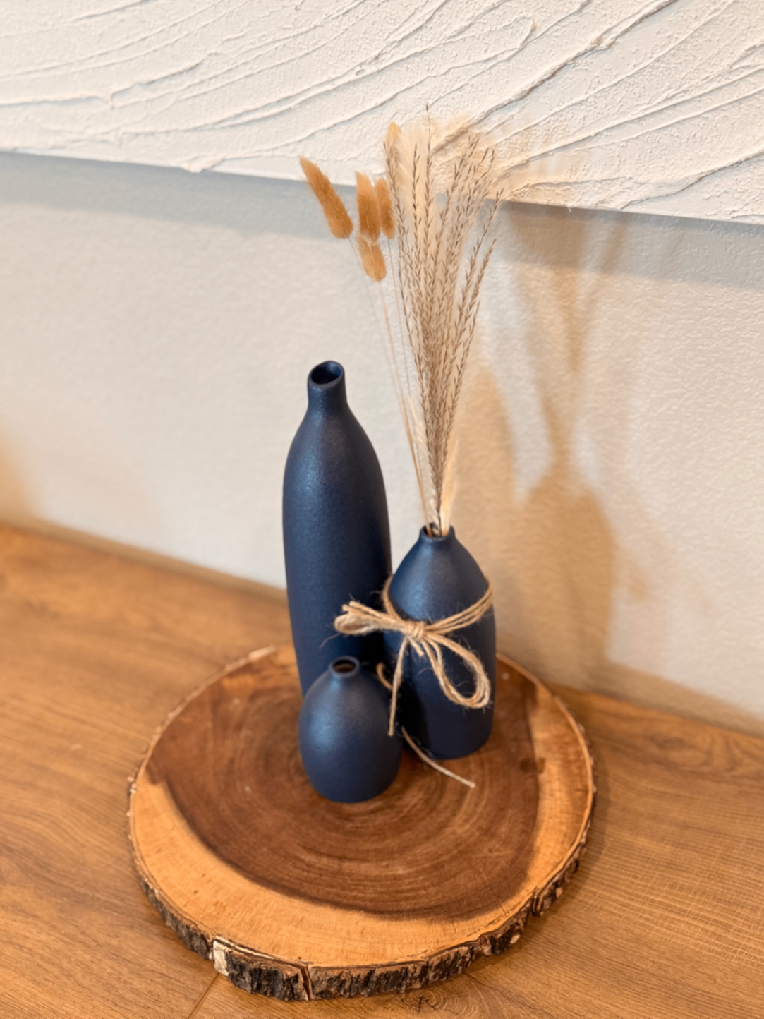 Decorative black vases and dried stems on a wood tray